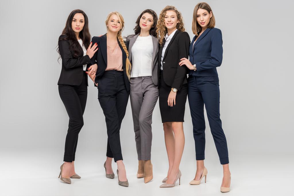 beautiful young businesswomen standing and smiling on grey background - Photo, Image