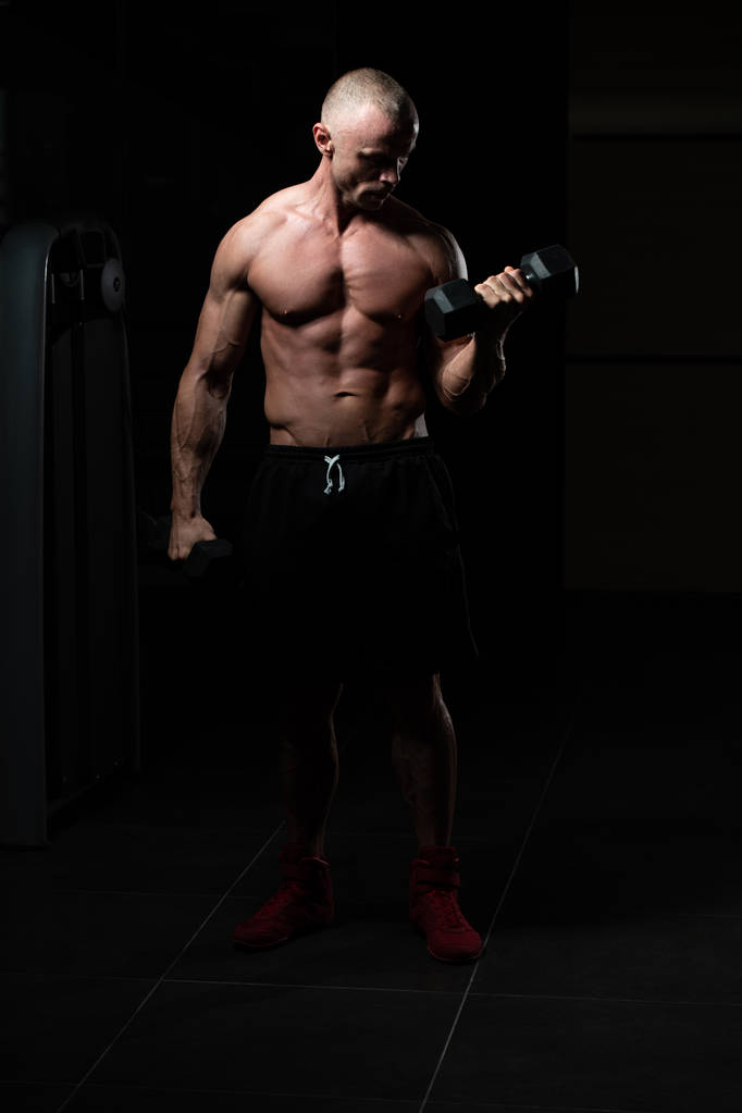 Mężczyzna działa Biceps w siłowni - hantle Concentration Loki - Zdjęcie, obraz