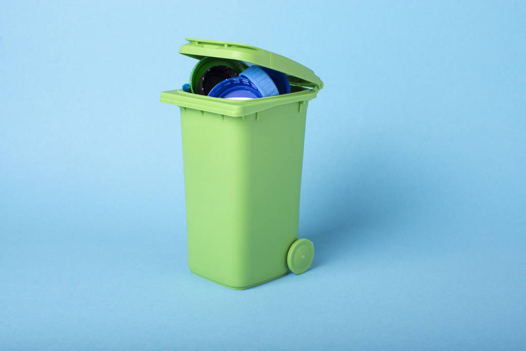Groene vuilnisbak op een blauwe achtergrond met plastic afval. Kunststof recycling. Recycling. Ecologisch concept. - Foto, afbeelding