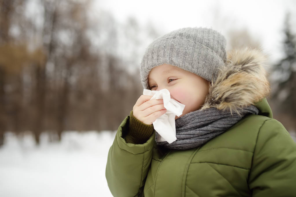 くしゃみリトルボーイとワイプは冬の公園でウォーキング中にナプキンで鼻します。インフルエンザ シーズンと風邪鼻炎。アレルギーの子供。病気の子供. - 写真・画像