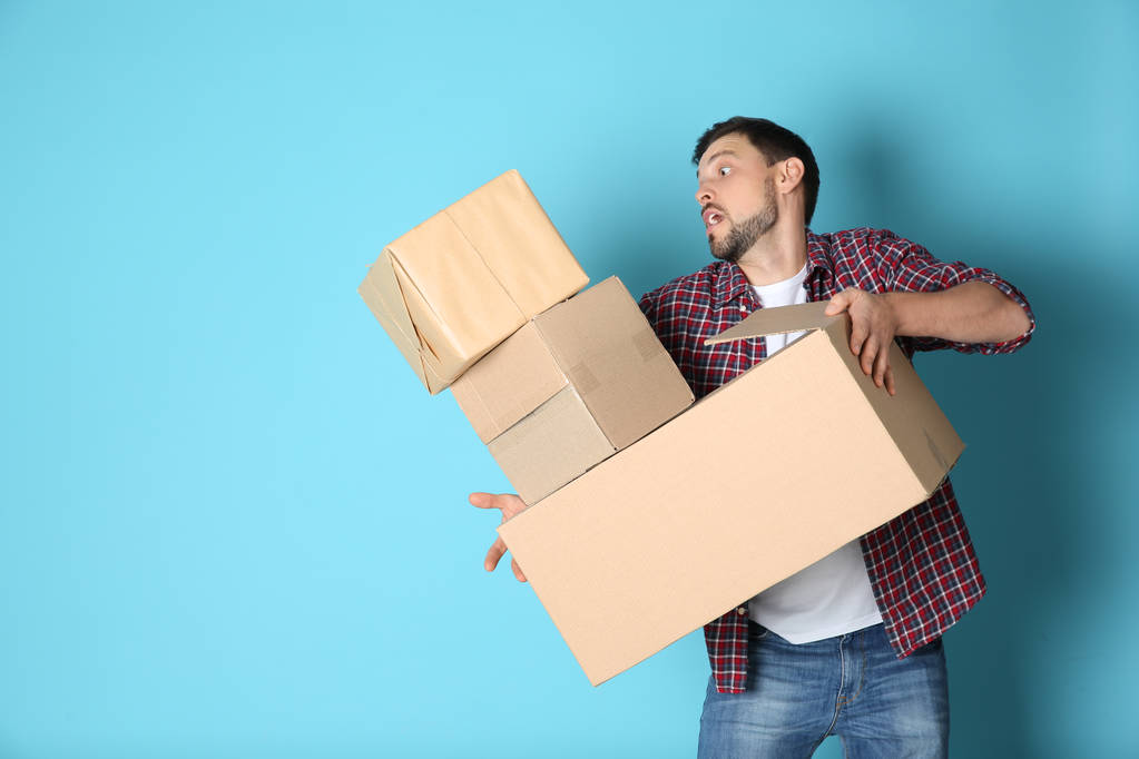 Man dropping moving boxes on color background. Space for text - Photo, Image