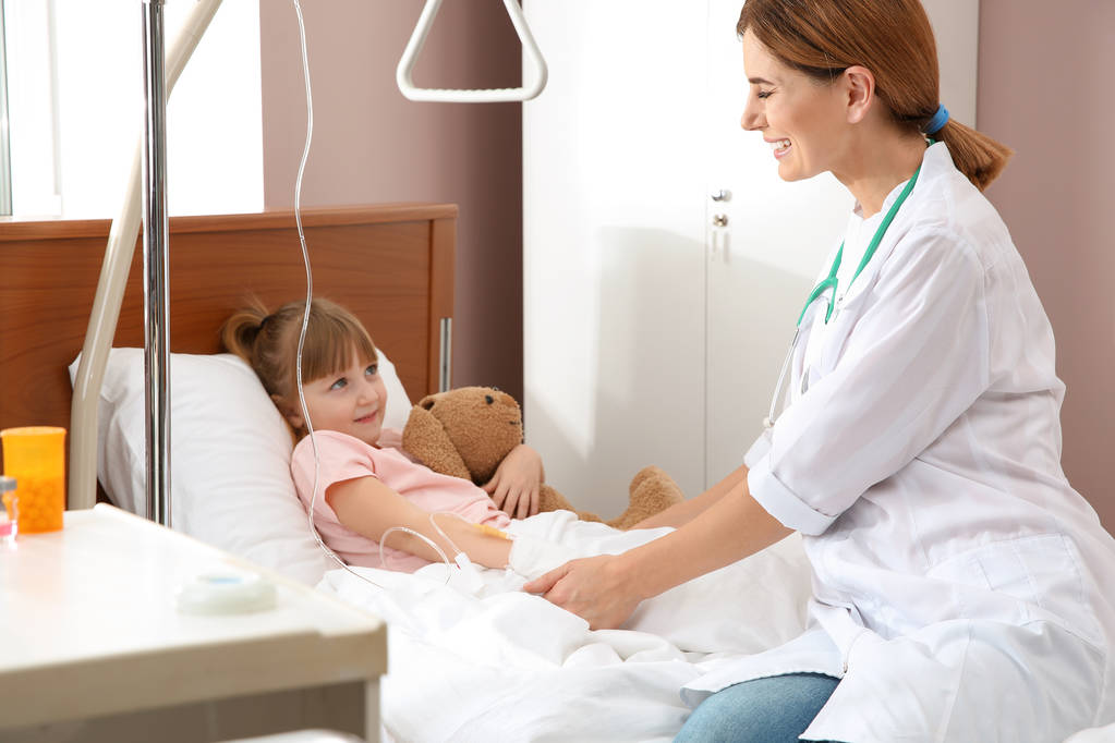 Лікар, який відвідує маленьку дитину з внутрішньовенним крапельницею в лікарні
 - Фото, зображення