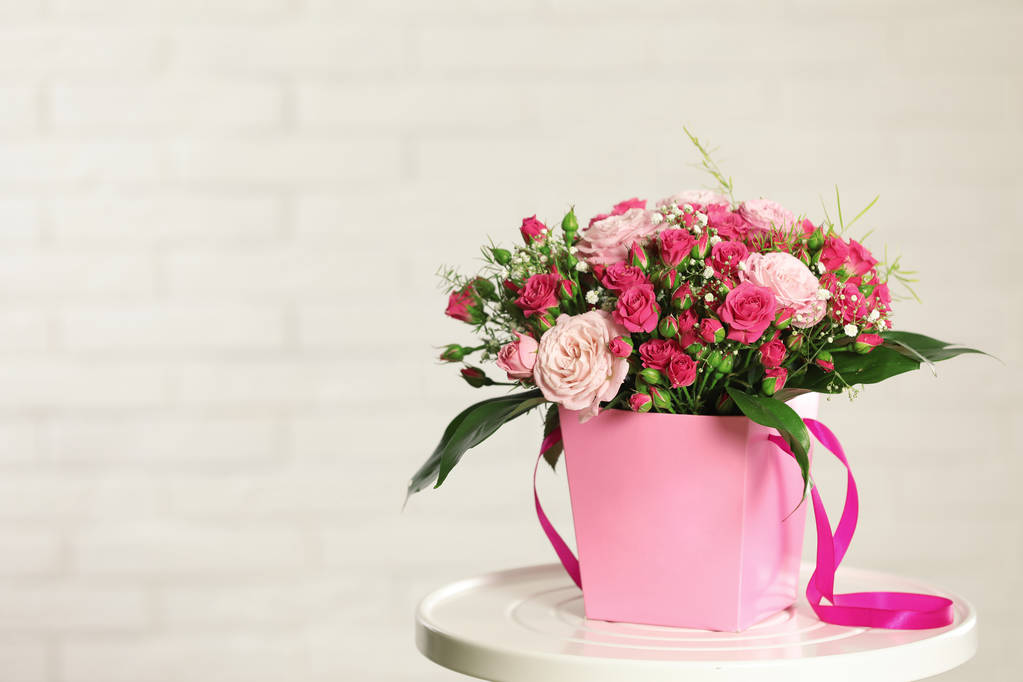 Krásnou kytici květin v papírové dárkové krabičce na stole proti světlé pozadí. Prostor pro text - Fotografie, Obrázek