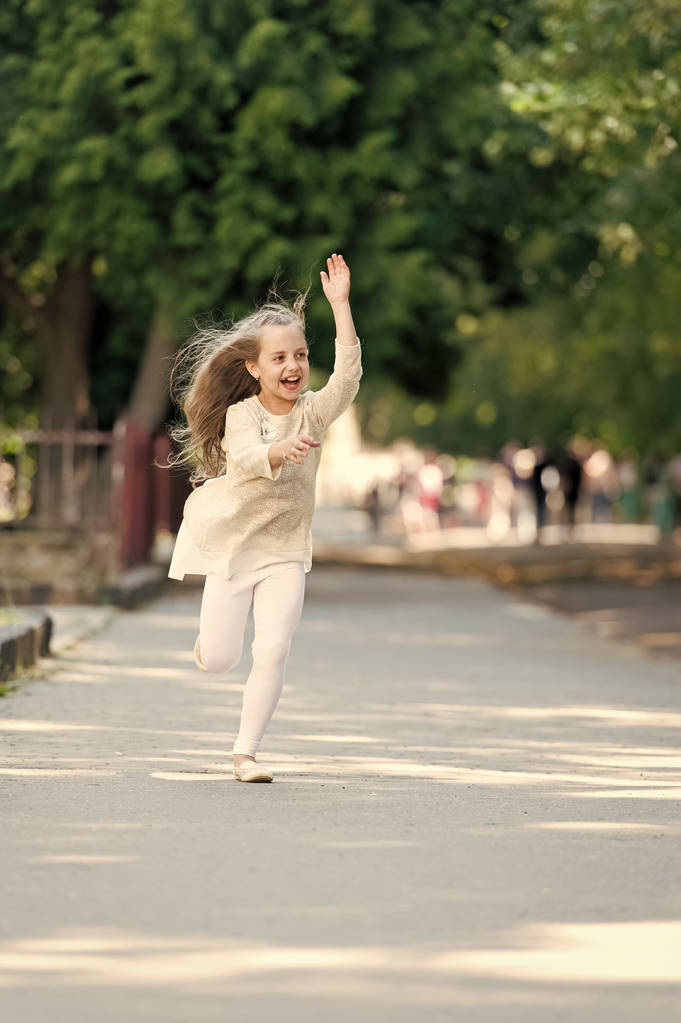 Ευτυχισμένος κορίτσι τρέχει στο πάρκο καλοκαίρι. Μικρό παιδί χαμόγελο με φέρουν τρίχωμα σε κίνηση. Δραστηριότητα του καλοκαιριού και την ευτυχία. Μόδα παιδί να διασκεδάσετε υπαίθρια. Ελευθερίας και της ενέργειας. Παιδική ηλικία δραστηριότητα και ενεργός παιχνίδια - Φωτογραφία, εικόνα