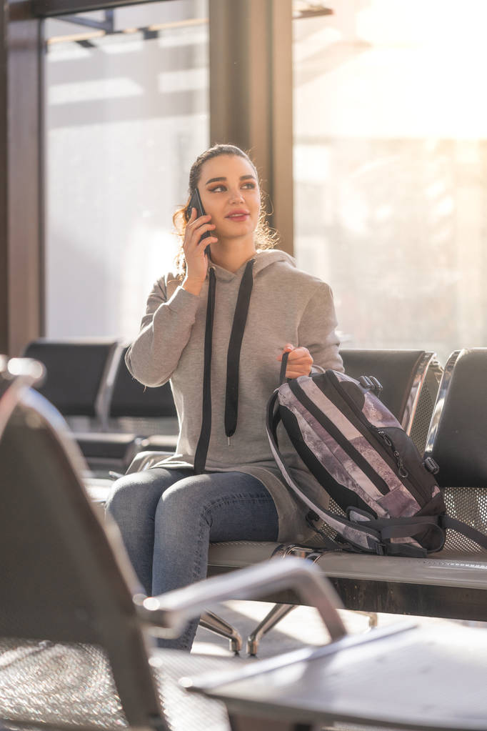 Mujer hermosa joven hablando por teléfono móvil en el aeropuerto de luz moderna
. - Foto, Imagen