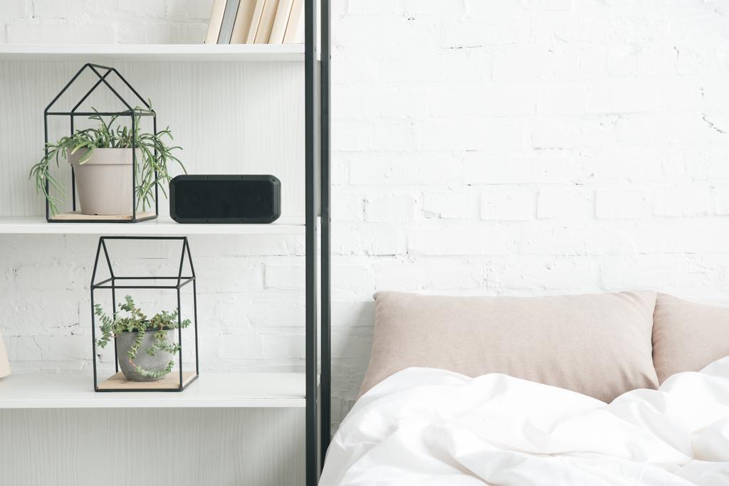 rack with plants, alarm clock and empty bed  - Photo, Image