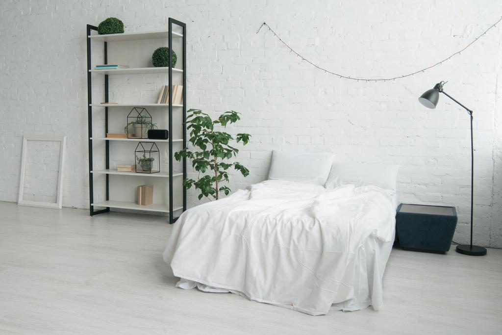 Интерьер спальни с подушками на кровати, тумбочка, лампа, рамка и стойка
 - Фото, изображение