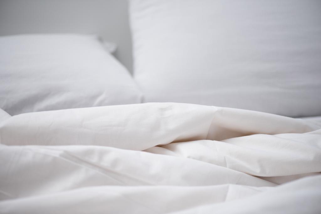 Enfoque selectivo de la cama vacía con manta blanca y almohada
 - Foto, imagen