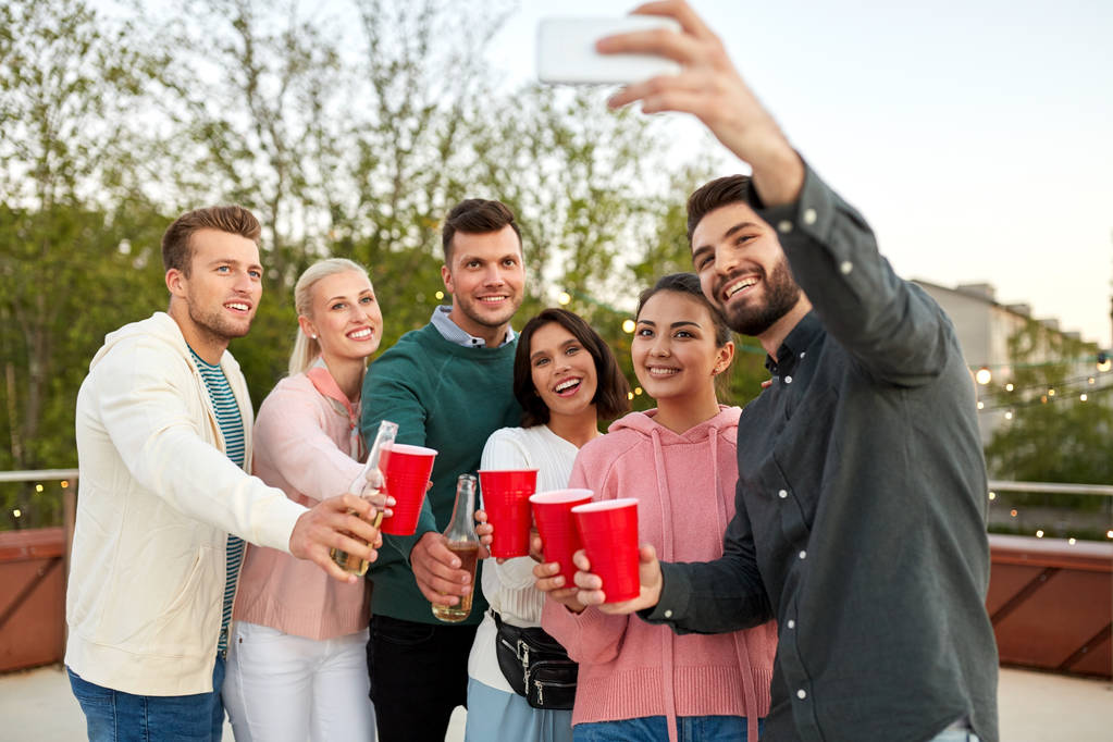 φίλοι με ποτά λήψη selfie σε πάρτι στον τελευταίο όροφο - Φωτογραφία, εικόνα