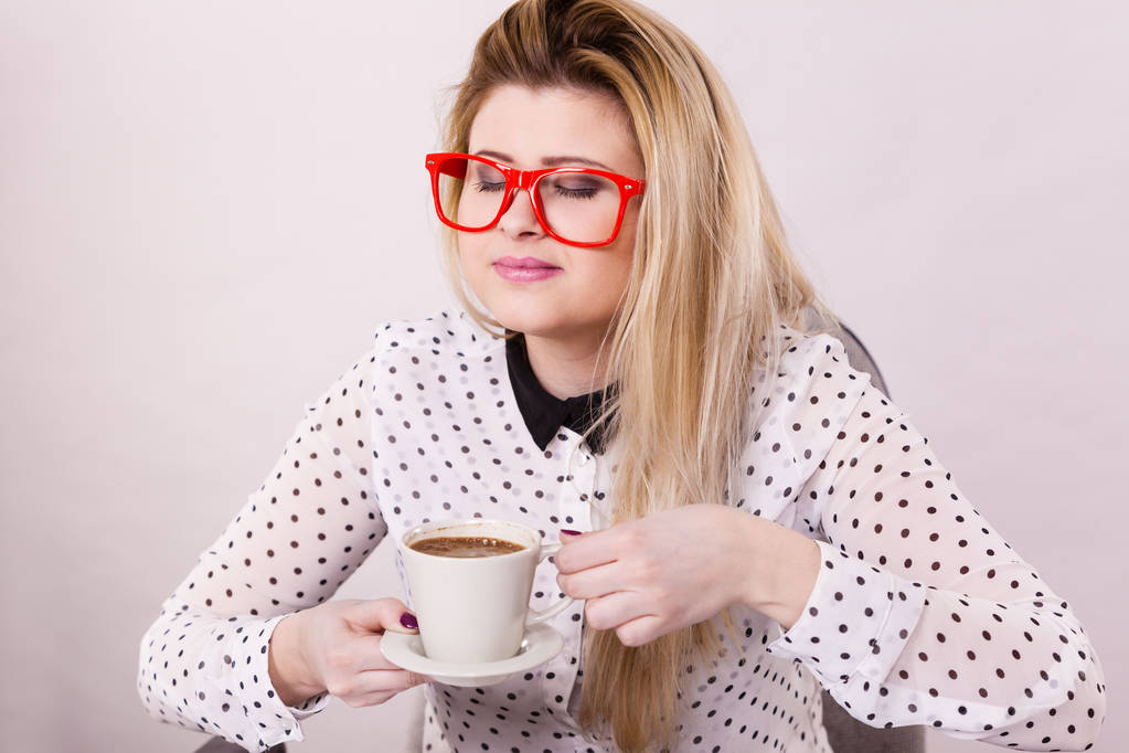 Joyeux jeune femme portant des lunettes au bureau boire du café chaud ou du thé profiter de son temps de pause pendant le travail. Détendez-vous. - Photo, image