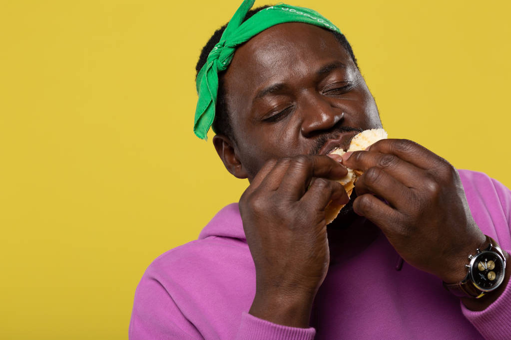 Porträt eines gutaussehenden Mannes, der Sandwich isst - Foto, Bild