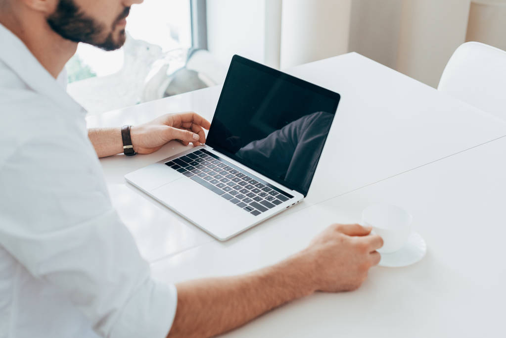 Man in white shirt drinking coffee and using laptop - Photo, Image