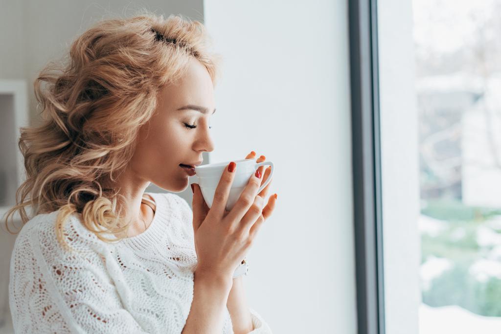 hübsche blonde Frau trinkt Kaffee mit geschlossenen Augen - Foto, Bild