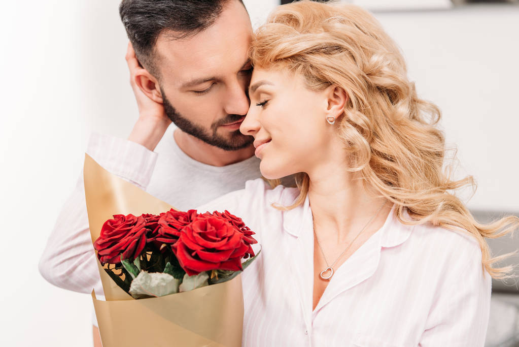 Rubia rizada mujer con rosas suavemente tocando novio
 - Foto, Imagen
