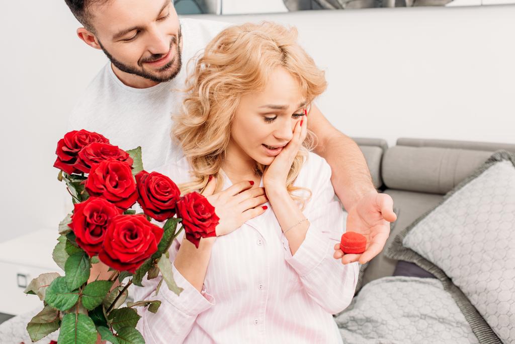 Чоловік з трояндами і кільцевою коробкою робить пропозицію подрузі
 - Фото, зображення
