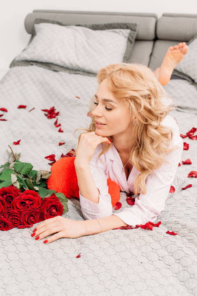 Impresionante joven acostada en la cama con rosas
 - Foto, Imagen