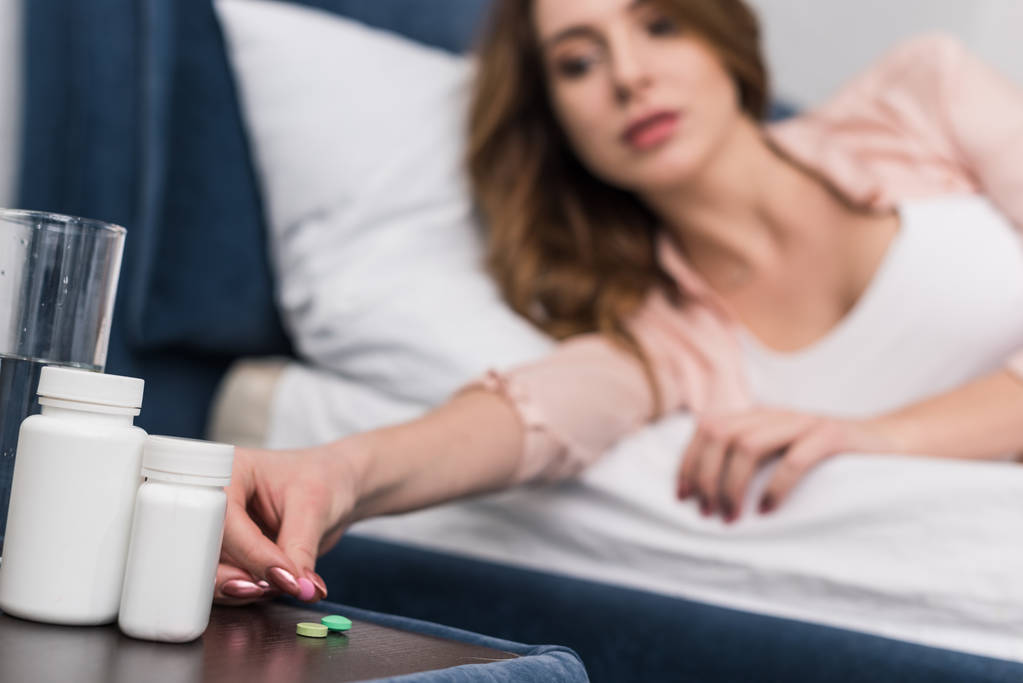 Ausgeschnittene Ansicht einer Frau im Bett, die Medikamente nimmt - Foto, Bild