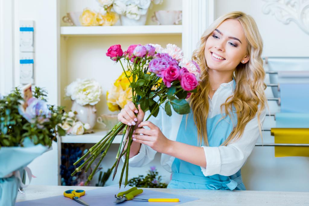schöne lächelnde Blumenhändlerin arrangiert Blumenstrauß im Blumenladen - Foto, Bild