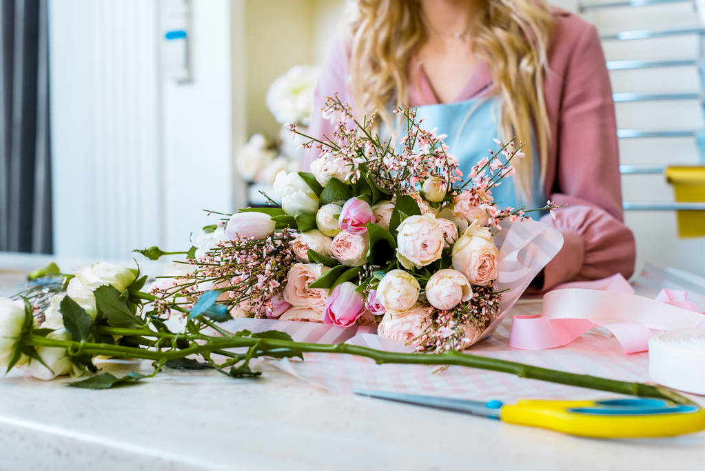 Teilansicht einer Blumenhändlerin, die einen Strauß Rosen im Blumenladen arrangiert - Foto, Bild