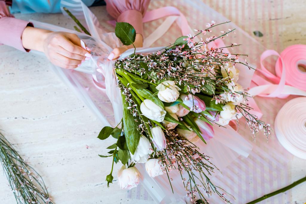 Ansicht von oben Blumenhändlerin arrangiert Strauß mit Tulpen und Rosen auf dem Tisch - Foto, Bild