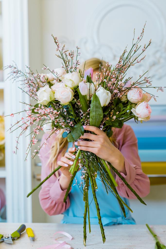 Blumenhändlerin hält Blumenstrauß mit weißen Rosen vor Gesicht im Blumenladen  - Foto, Bild