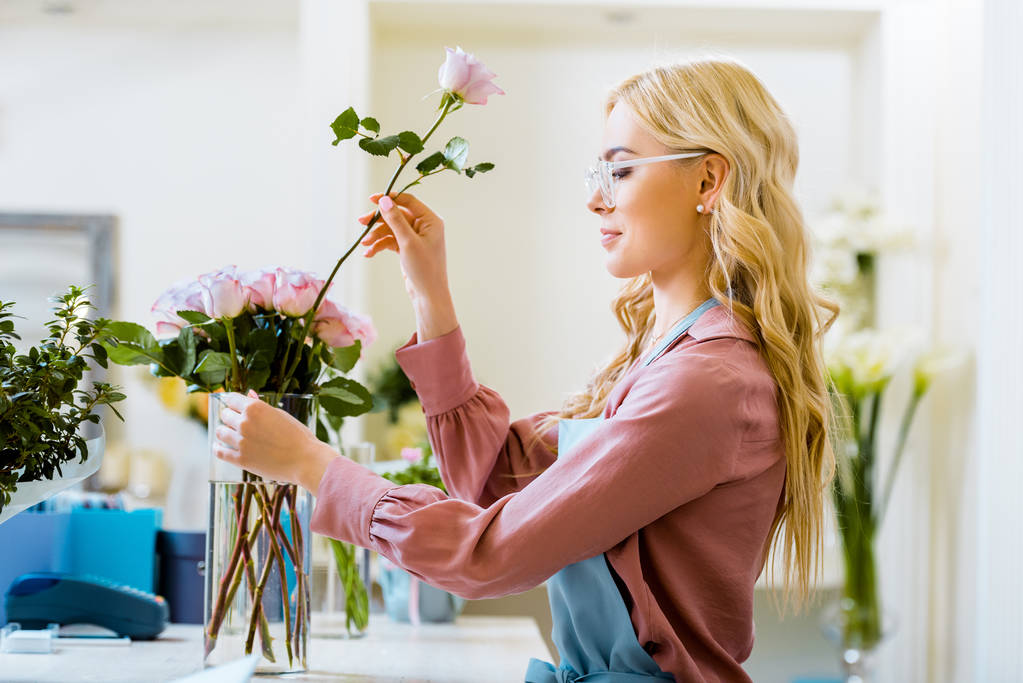 buket çiçek dükkanında pembe koyarak güzel kadın çiçekçi gül - Fotoğraf, Görsel