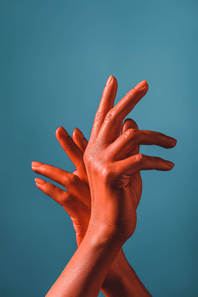 Teilansicht einer gestikulierenden Frau mit korallenfarbenen Händen auf blauem Hintergrund, Farbe des Konzepts 2019 - Foto, Bild