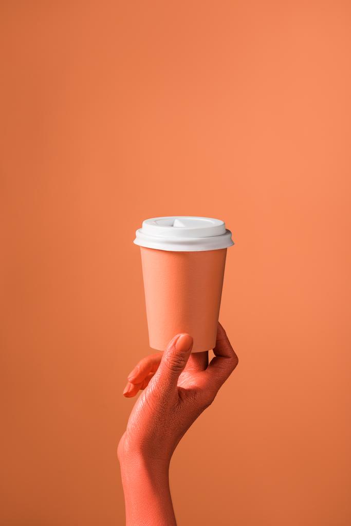 vista parcial de la mano femenina con taza de papel de coral sobre fondo de coral, concepto de color de 2019
 - Foto, Imagen