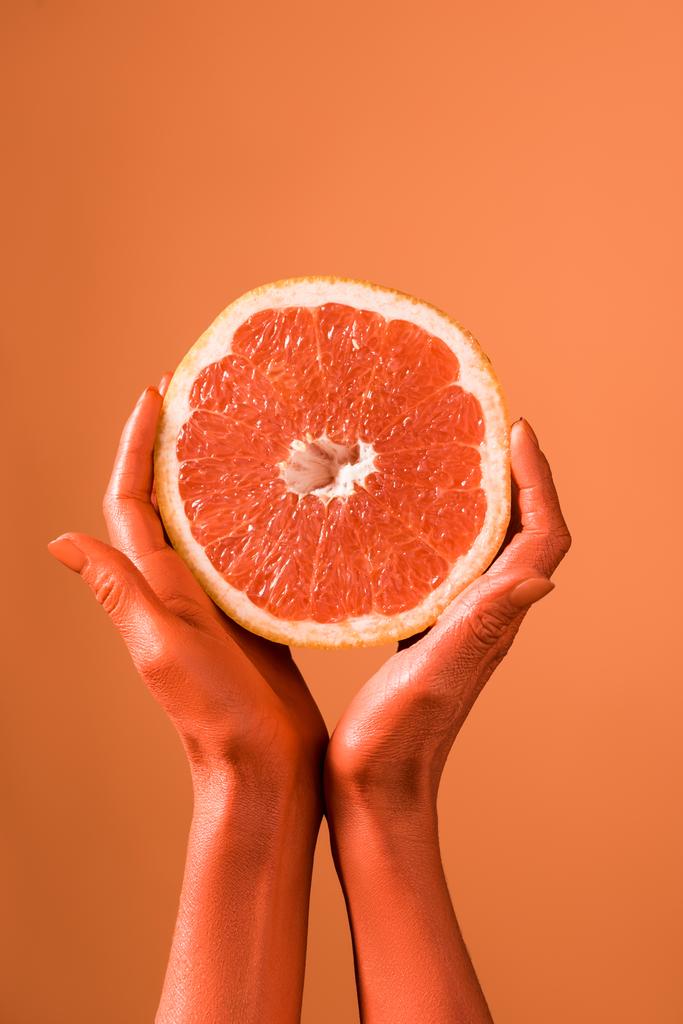 oříznutý pohled na korálové barvy ženských rukou s grapefruity polovinu na korálových pozadí, barva konceptu 2019 - Fotografie, Obrázek