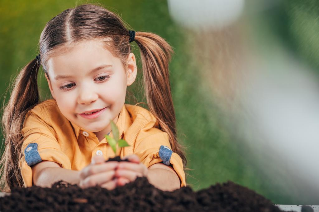 Selektivní fokus dítěte výsadbě mladých rostlin na rozostřeného pozadí, koncept den země - Fotografie, Obrázek