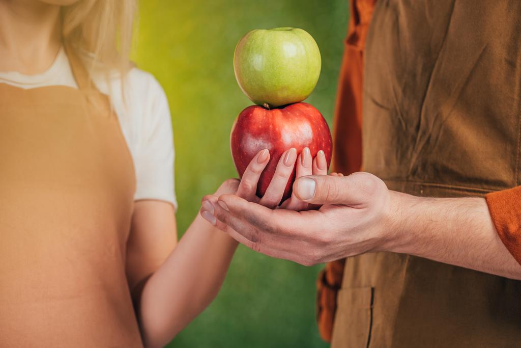 частичный взгляд мужчины и женщины, держащих яблоки на размытом фоне, концепция Дня Земли
 - Фото, изображение