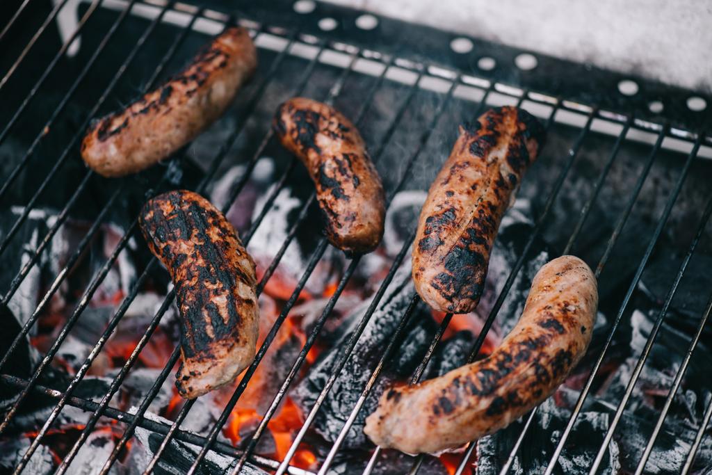 foyer sélectif de saucisses savoureuses grillées dispersées en fumée sur grille de barbecue
 - Photo, image