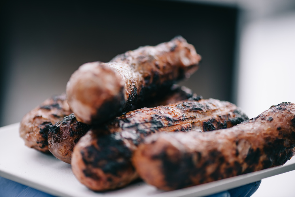 selective focus of delicious meat sausages with crust on white plate  - Photo, Image