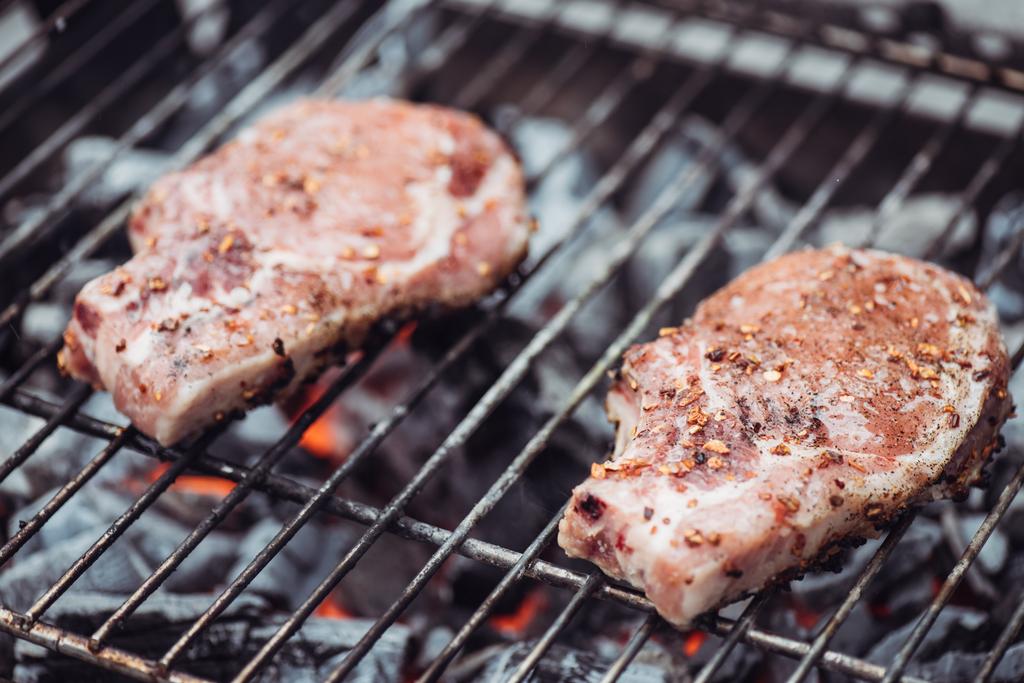 Selektivní fokus šťavnaté syrové steaky grilování grilovací mřížky s kouřem - Fotografie, Obrázek