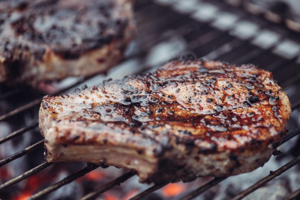 selektiver Fokus von saftig würzigem Steakgrillen auf Grillrost mit Rauch - Foto, Bild