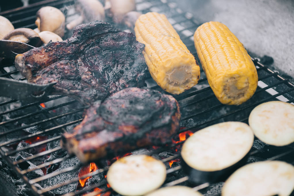 foyer sélectif de pinces à épiler et de steaks juteux et savoureux grillades sur grille de barbecue avec champignons, maïs et aubergines tranchées
 - Photo, image