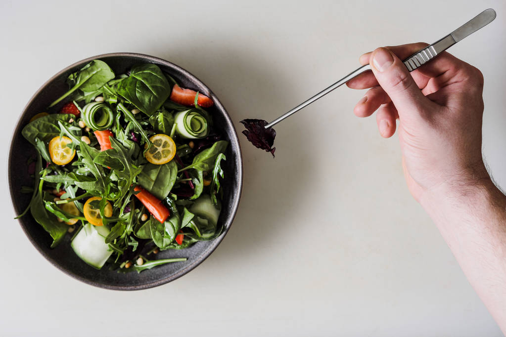 Bir erkek Şef salatası siyah önlük bir restoran mutfakta süsle. Beyaz kesme tahtası. - Fotoğraf, Görsel
