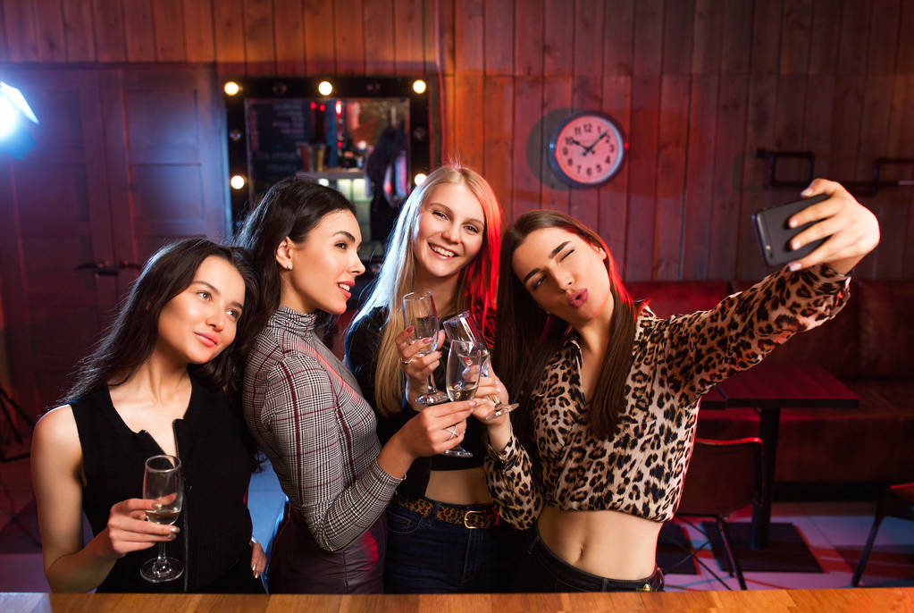 Ragazze allegre si divertono prendendo selfie e bevendo cocktail nel bar
 . - Foto, immagini