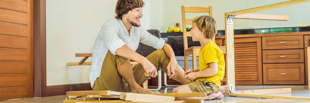 Isä ja poika kokoavat huonekaluja. Poika auttaa isäänsä kotona. Onnellinen perhekonsepti BANNER, LONG FORMAT
 - Valokuva, kuva