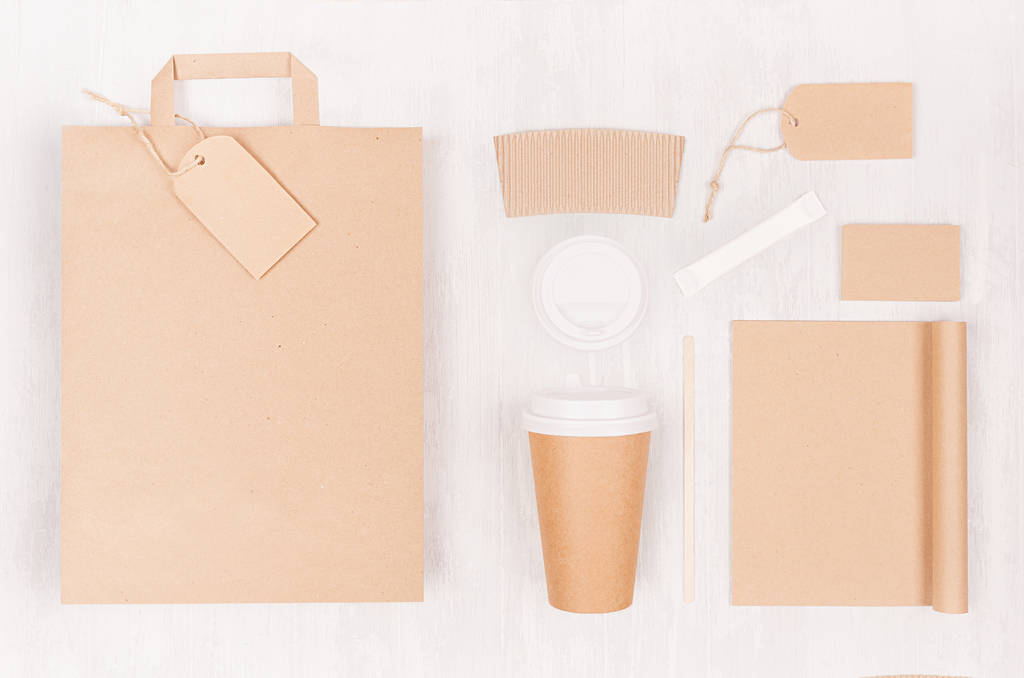 Eco friendly coffee template for design, advertising and branding - brown paper cup and blank bag, notebook, label, card, cap, sugar on white wood board, top view. - Photo, Image