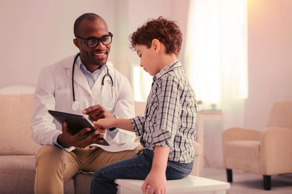 Child explaining his symptoms to the doctor using a tablet - Photo, Image