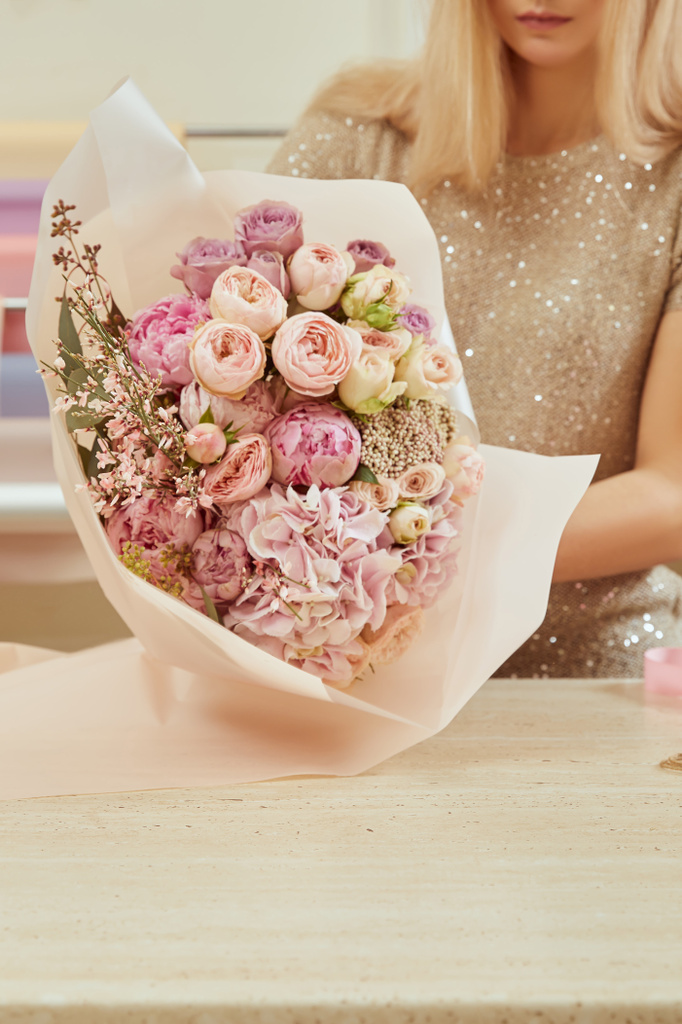 vue partielle de l'emballage de fleuriste avec bouquet de papier de roses et pivoines à l'espace de travail
 - Photo, image