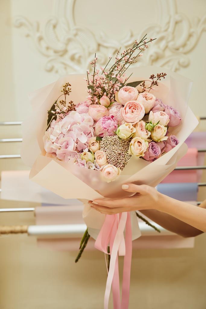 обрезанный вид флориста, держащего букет роз и пионов на рабочем месте
 - Фото, изображение