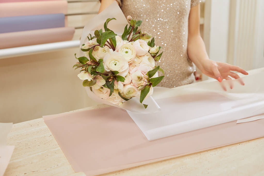 partial view of florist wrapping bouquet of white peonies at workspace - Photo, Image