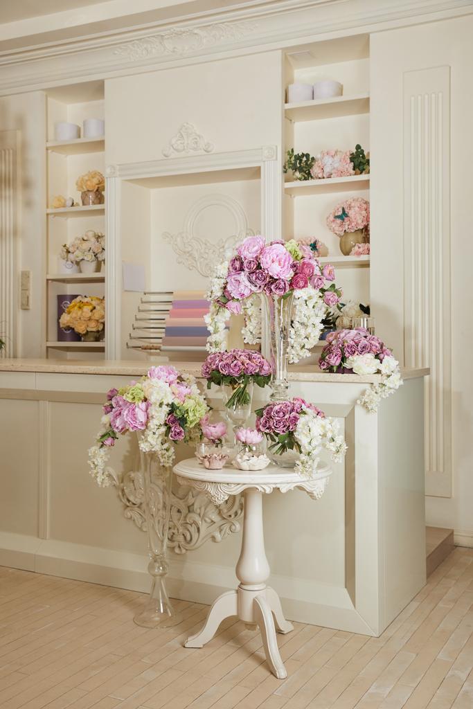Innenraum mit Regal, Tisch und Blumen in Glasvasen - Foto, Bild