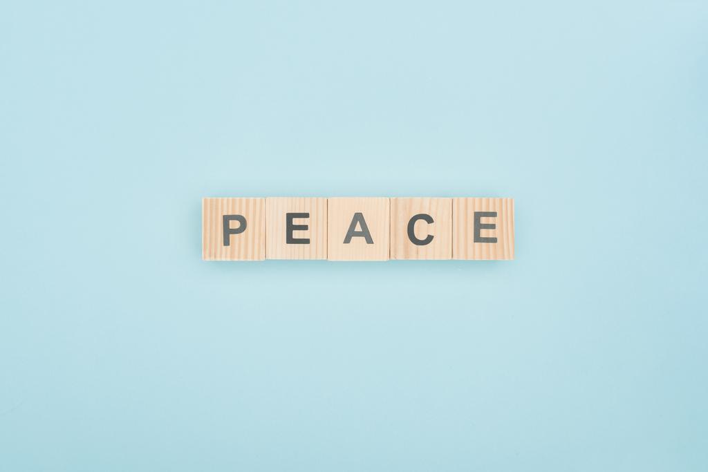 top view of peace lettering made of wooden cubes on blue background - Photo, Image