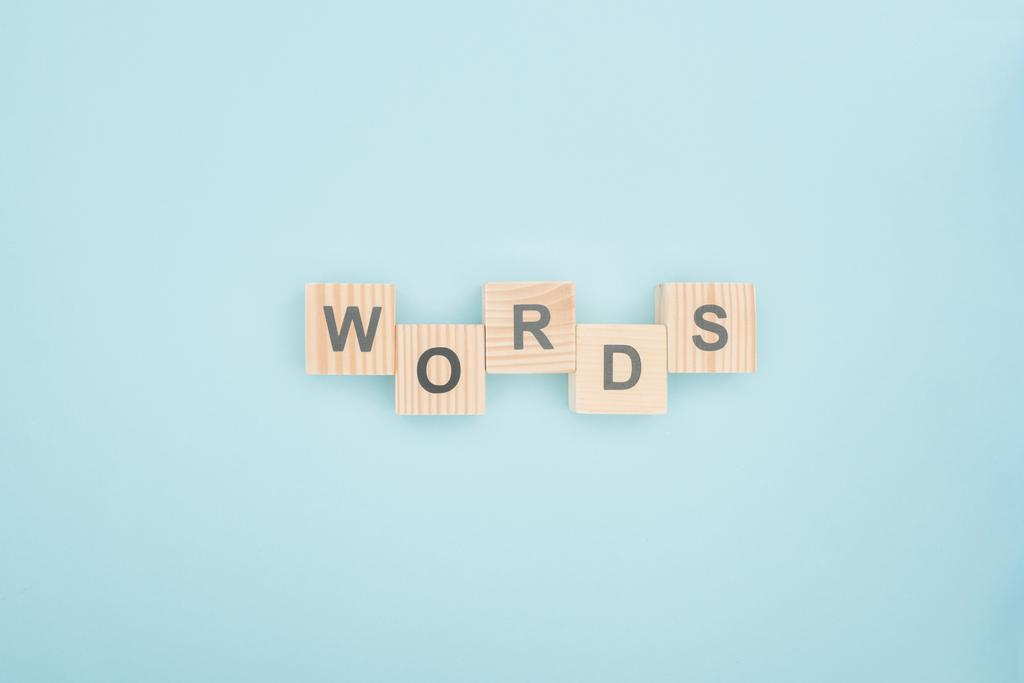 felülnézet szavakkal, betűkkel készült fa tömb a kék háttér - Fotó, kép