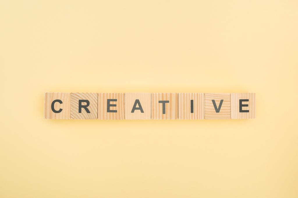 top view of creative lettering made of wooden cubes on yellow background - Photo, Image