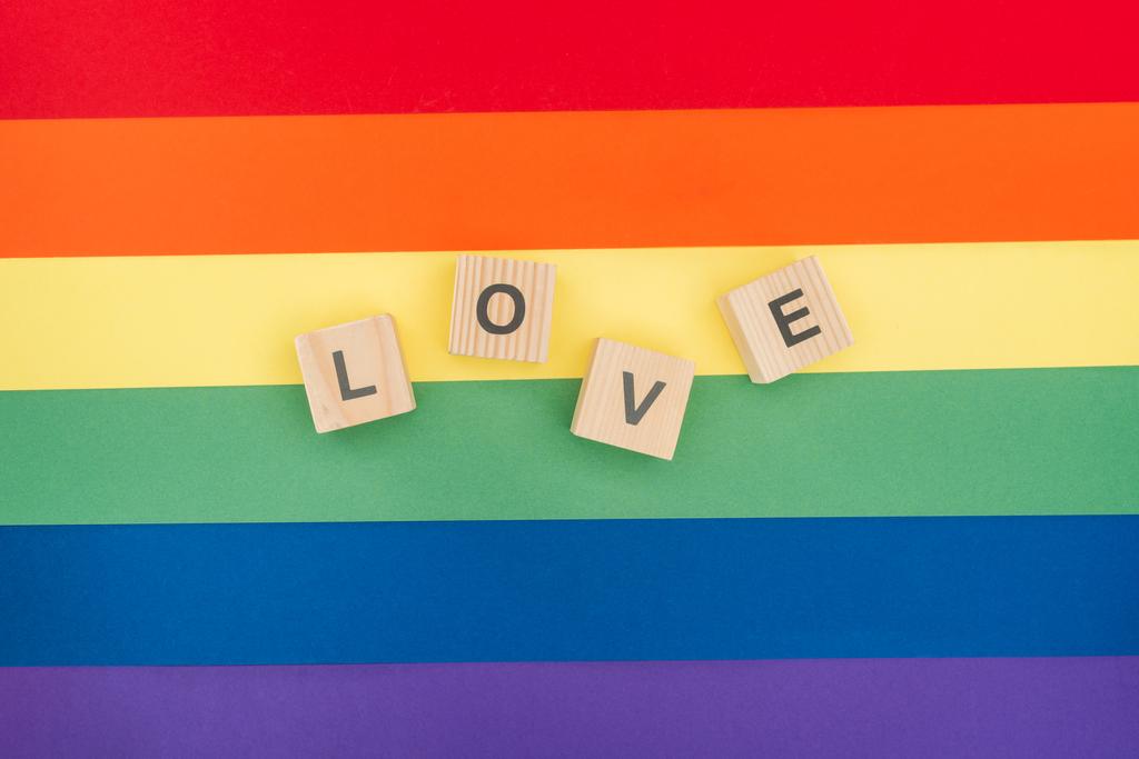 Ansicht der Liebe Schriftzug aus Holzwürfeln auf Papier Regenbogen Hintergrund - Foto, Bild