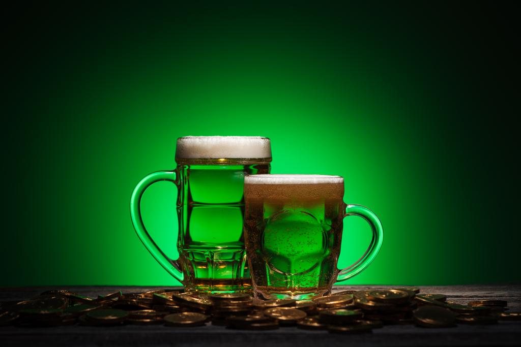 Biergläser stehen neben Goldmünzen auf grünem Hintergrund - Foto, Bild